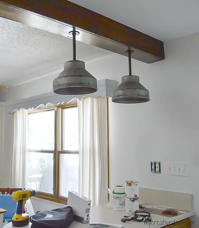 Looking to update the lighting in your kitchen? These DIY Light Fixtures upcycle farm pieces to create custom farmhouse lighting in this kitchen.
