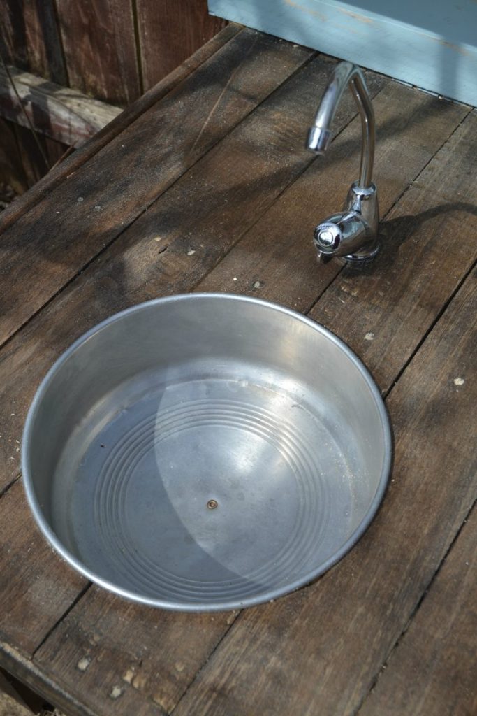 Pallet Wood Projects are so much fun because the wood is cheap and the possibilities are endless. Click over to see how easy it is to make a pallet wood mud kitchen for the kids!