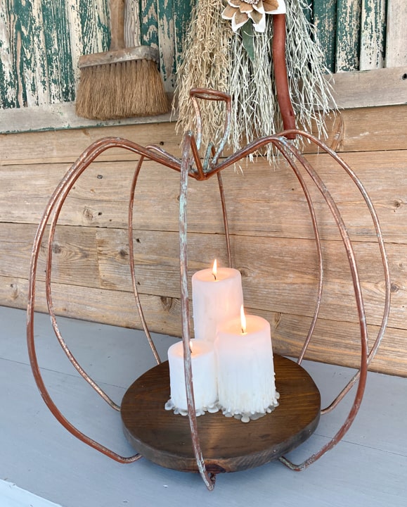 This DIY Pumpkin Lantern came together with a yard sale find, scrap wood from the garage, and some inexpensive pillar candles from Walmart.