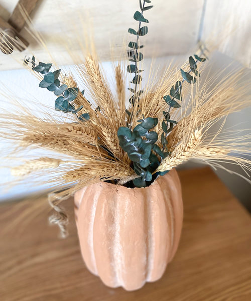 This DIY Fall Centerpiece gives the look of a terra cotta pumpkin vase for a lot less by using paper mache, paint, and baking soda!