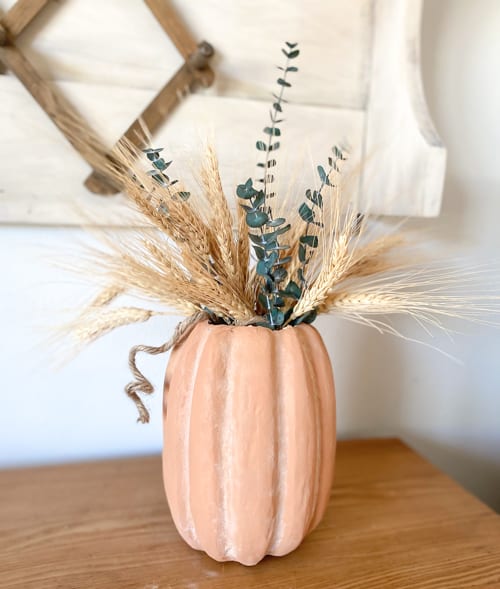 This DIY Fall Centerpiece gives the look of a terra cotta pumpkin vase for a lot less by using paper mache, paint, and baking soda!