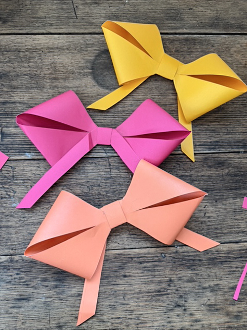 Learn how easy it is to make DIY paper bows with hot glue, paper, and scissors. Make them for birthdays, gifts, Valentine's Day decor, or turn them into garlands.