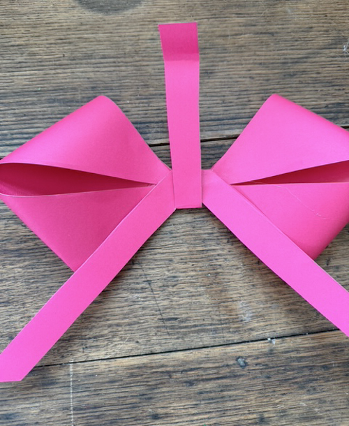 Learn how easy it is to make DIY paper bows with hot glue, paper, and scissors. Make them for birthdays, gifts, Valentine's Day decor, or turn them into garlands.