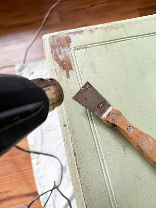 Learn how to remove paint from vintage table surfaces before repainting. Step-by-step tutorial using a heat gun and sanding for best results.