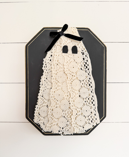 DIY Halloween Ghost Decor is easy to make with a wood plaque, lace trim, and a few simple supplies. Create this cute DIY ghost wall hanging on a budget.