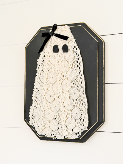 DIY Halloween Ghost Decor is easy to make with a wood plaque, lace trim, and a few simple supplies. Create this cute DIY ghost wall hanging on a budget.