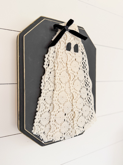 DIY Halloween Ghost Decor is easy to make with a wood plaque, lace trim, and a few simple supplies. Create this cute DIY ghost wall hanging on a budget.