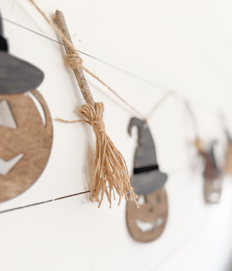 Make this DIY Rustic Halloween Garland with Dollar Tree wood cutouts, stain, witch hats, velvet ribbon, twine, and mini witch brooms.