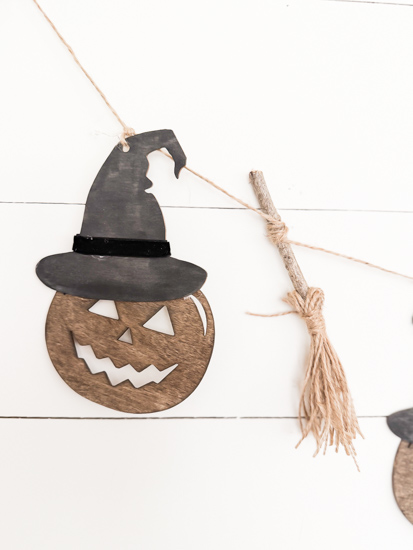 Make this DIY Rustic Halloween Garland with Dollar Tree wood cutouts, stain, witch hats, velvet ribbon, twine, and mini witch brooms.