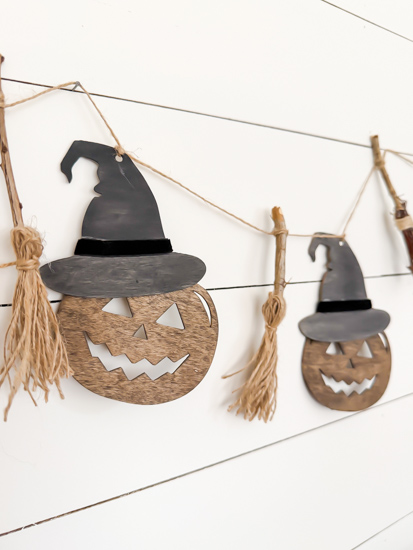 Make this DIY Rustic Halloween Garland with Dollar Tree wood cutouts, stain, witch hats, velvet ribbon, twine, and mini witch brooms.