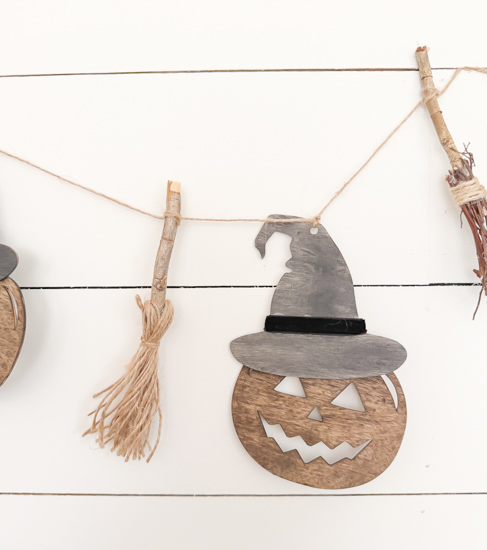Make this DIY Rustic Halloween Garland with Dollar Tree wood cutouts, stain, witch hats, velvet ribbon, twine, and mini witch brooms.