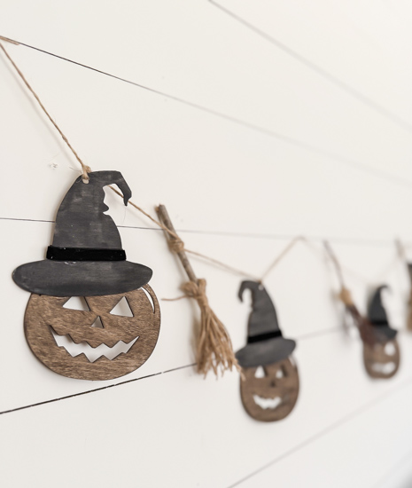 Make this DIY Rustic Halloween Garland with Dollar Tree wood cutouts, stain, witch hats, velvet ribbon, twine, and mini witch brooms.